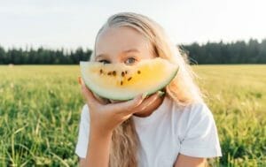 Yellow Watermelon: Yes, It's Real! Here's Everything You Need to Know 1 young girl eating yellow watermelon in farm field
