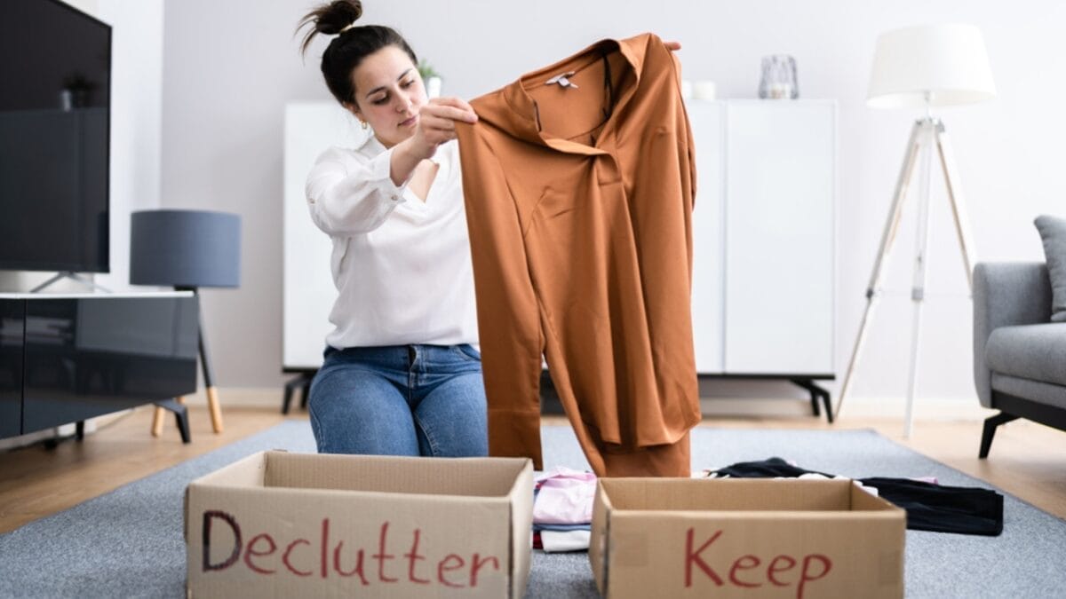 12 Tiny Habits to Prevent Your Home from Descending into Clutter Chaos - woman decluttering clothes dp473148856