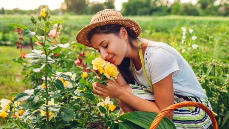 A Look at 10 Folklore-Inspired Gardening Traditions & Their Origins 6 A Look at 10 Folklore-Inspired Gardening Traditions & Their Origins - woman smelling flowers in garden ss1786223270