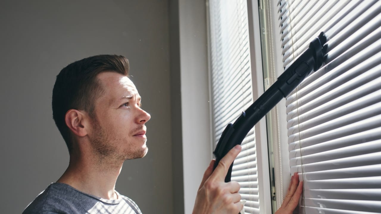 Avoid Costly Repairs: 16 Home Tasks You Shouldn’t Skip 15 Avoid Costly Repairs: 16 Home Tasks You Shouldn’t Skip - Man cleaning dust from window blind ss1966368577