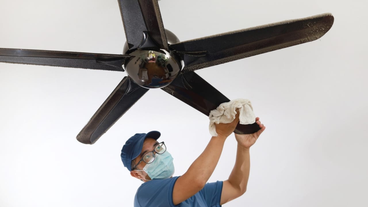 15 Easy Winterization Tips to Protect Your Home & Wallet - male cleaning ceiling fan ss1899194818