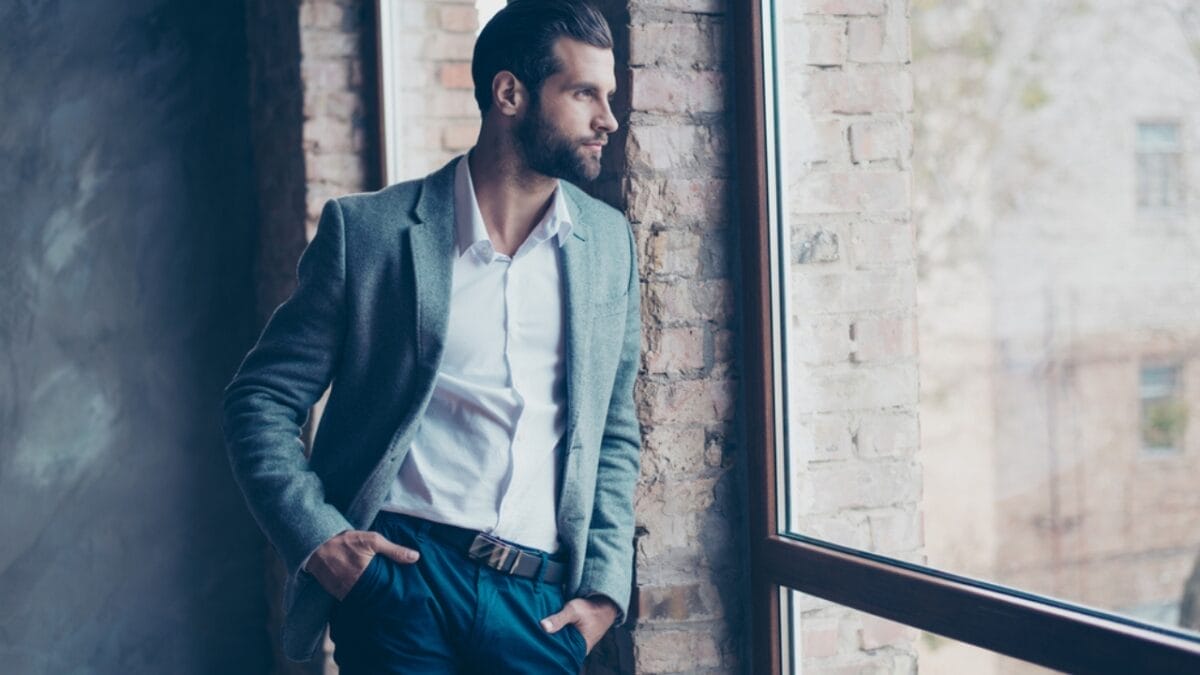 7 Stress-Busting Benefits of Worry Stones to Help Calm Your Mind - man leaning on wall smiling ss646467355