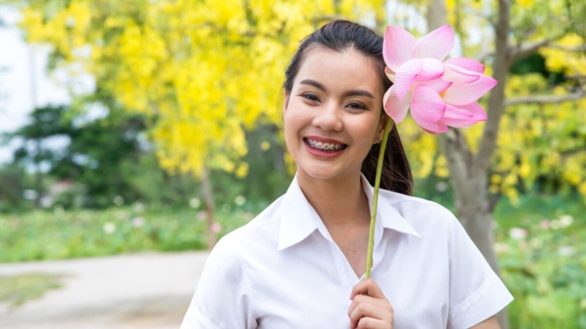 Lessons From the Lotus: The Meaning & Symbolism Behind These Flowers - woman holding lotus flower ss1083057491