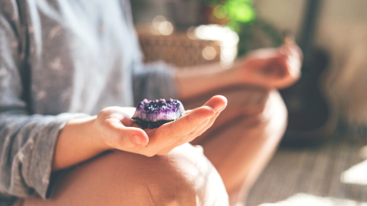 7 Stress-Busting Benefits of Worry Stones to Help Calm Your Mind - woman meditating with stone ss1703924659
