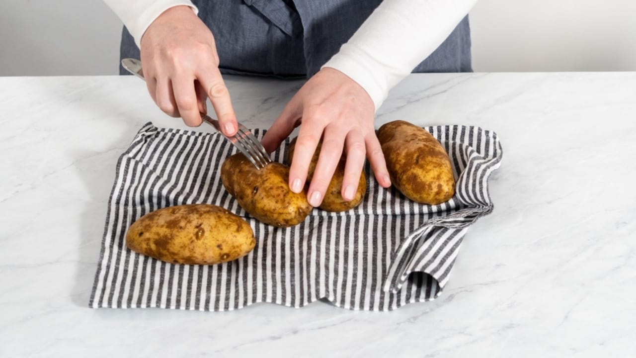 10 Tips for Baking Potatoes Like a Pro—And a Microwave Method When You’re in a Pinch 5 10 Tips for Baking Potatoes Like a Pro—And a Microwave Method When You’re in a Pinch - poking potato with fork ss2358816063