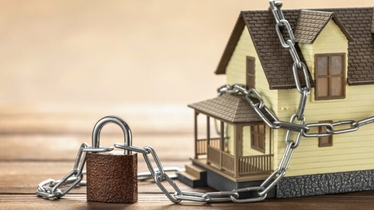 Don’t Get Fooled: Safeguard Your Home Title from Scams 6 Don’t Get Fooled: Safeguard Your Home Title from Scams - House tied with a chain and a closed lock ss2049458297