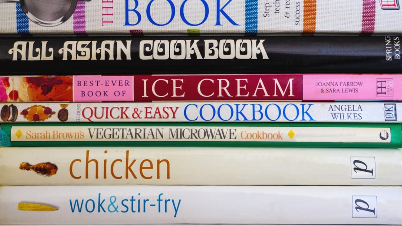 10 Things You Should Never Store in Low Kitchen Cabinets - pile of cookbook ss1824115340