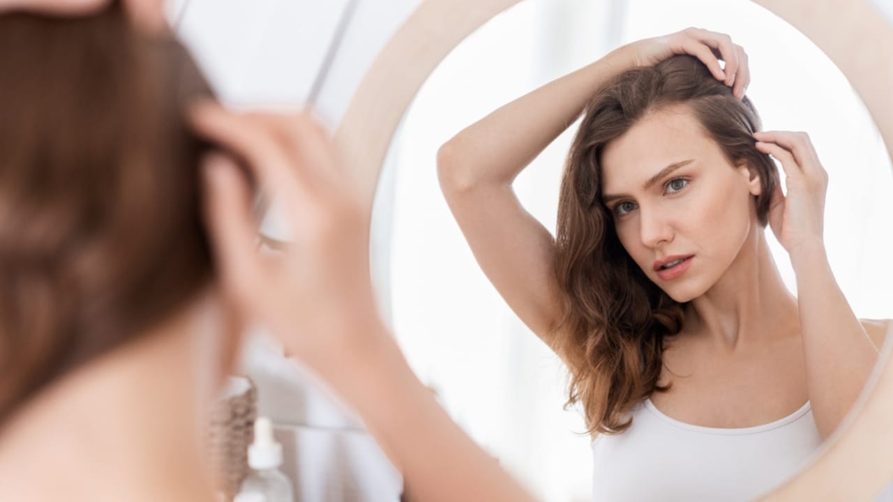 Onion Juice Stimulates Hair Growth— Experts Share the Science Behind It 4 Onion Juice Stimulates Hair Growth— Experts Share the Science Behind It - woman checking scalp in the mirror dp387998538