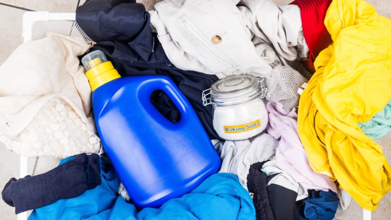15 Natural Cleaning Recipes That Rival Chemical Products - Baking soda with detergent and pile of dirty laundry dp85976366