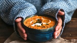 21 Hearty Protein-Packed Soups That Will Keep Your Tummy & Tastebuds Happy 1 21 Hearty Protein-Packed Soups That Will Keep Your Tummy & Tastebuds Happy - Female hands holding a bowl of pumpkin soup ss1192495123