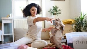 Declutter Your Home in Record Time with This Expert-Approved 20-Minute Rule 1 Declutter Your Home in Record Time with This Expert-Approved 20-Minute Rule - Young woman sorting clothes dp450883166