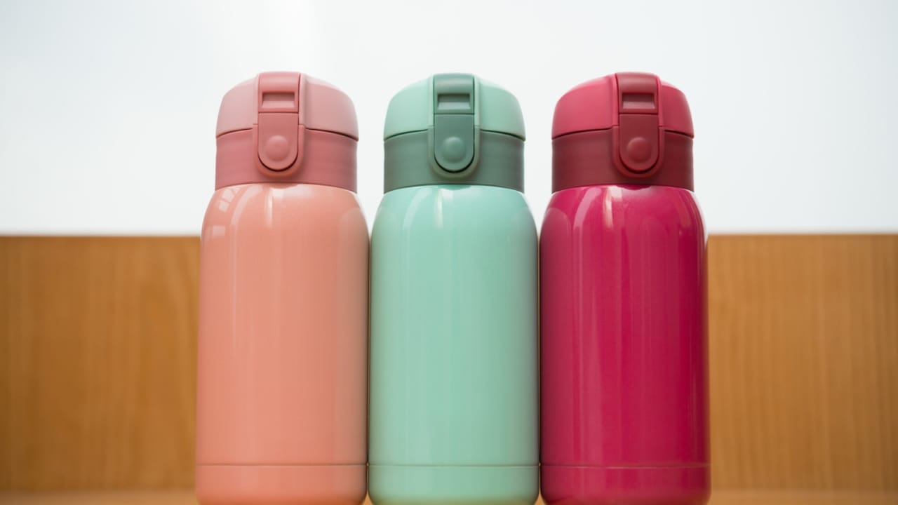 54% of Americans Face Disaster Risks: 18 Goodwill Essentials for Budget Survival Kits - colorful thermos on a wooden table ss431183254