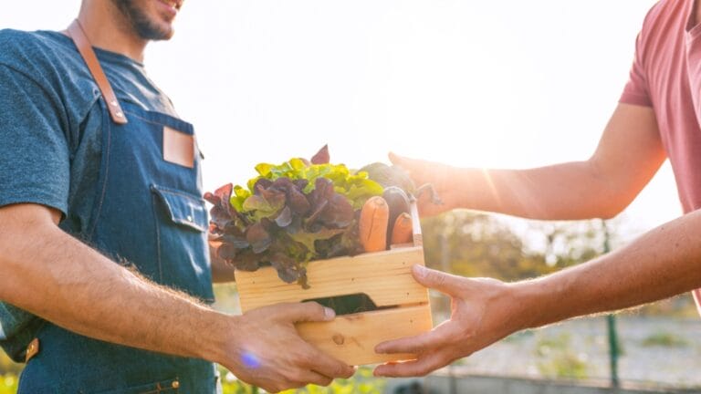 $140K on 1.5 Acres: 10 Strategies for Small Farm Success 4 $140K on 1.5 Acres: 10 Strategies for Small Farm Success - man holding vegetables talking ss1214671537