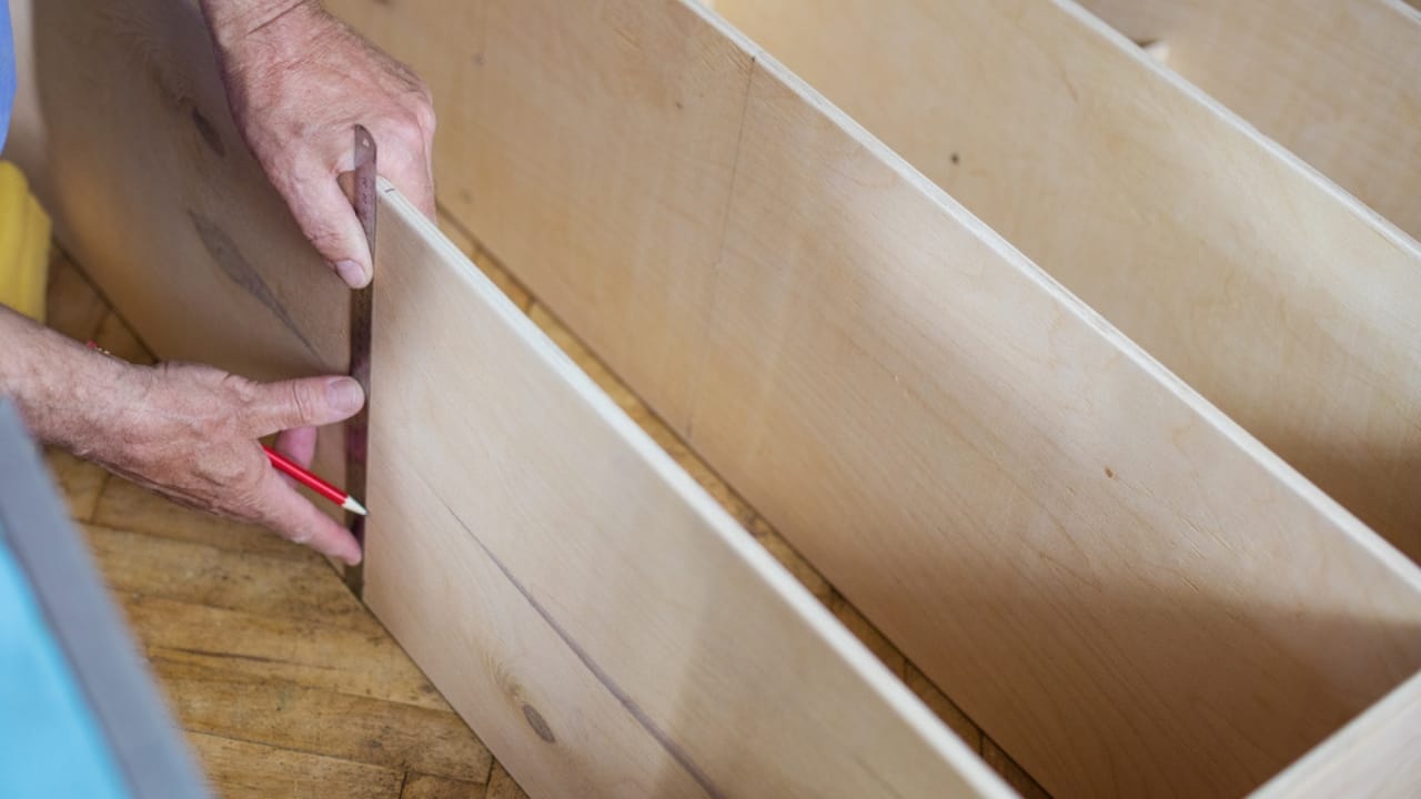 Maximize Your Garage Space with These 18 Simple DIY Organization Projects - man measuring wooden shelf with ruler ss655601155