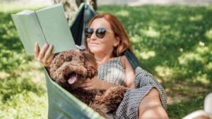 For Brainy Dog Lovers: 25 Highly Intelligent Breeds to Consider - woman reading with maltipoo dog in hammaock ss2482349293