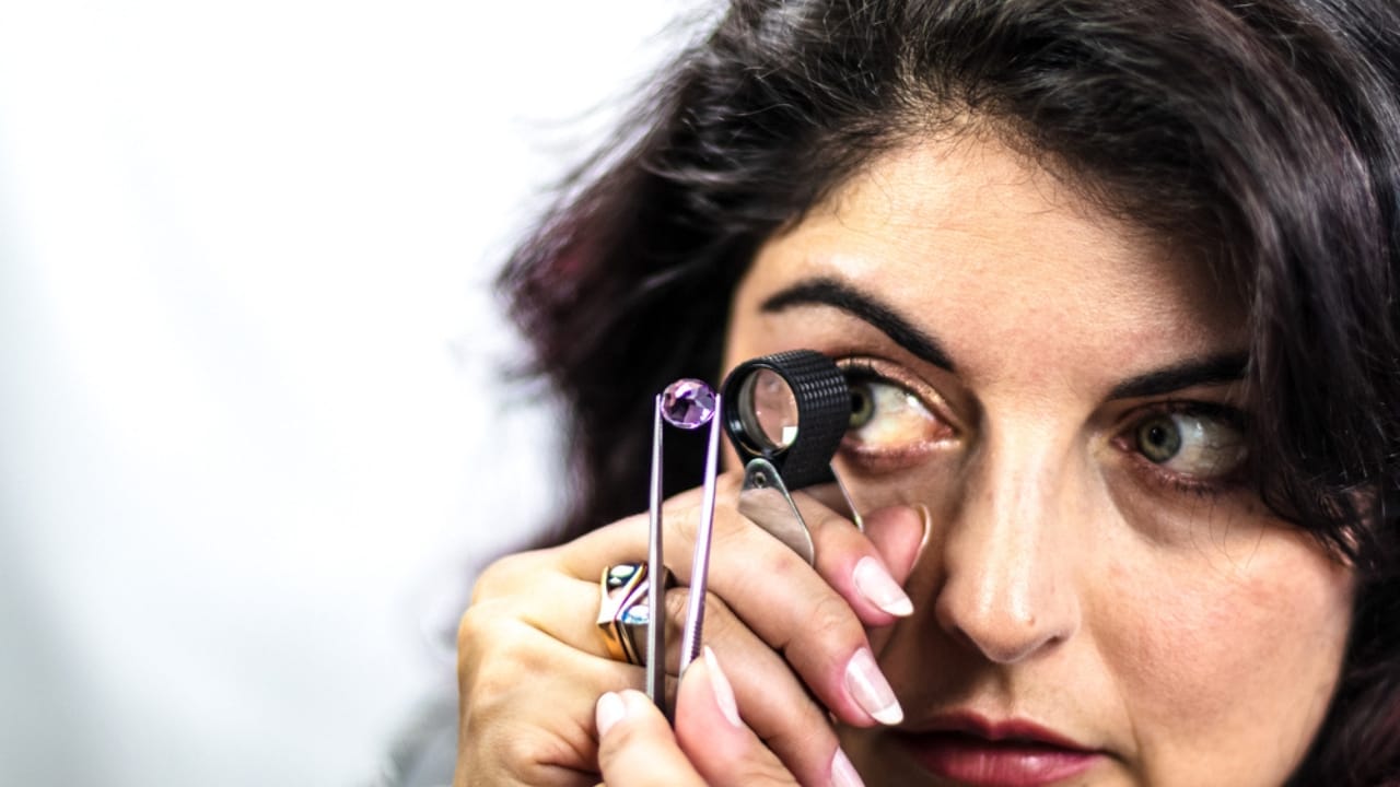 This Gemstone, Rarer Than Diamonds, Was Found by Accident 6 This Gemstone, Rarer Than Diamonds, Was Found by Accident - Gemologist woman studying purple gemstone dp421418710 dnoh