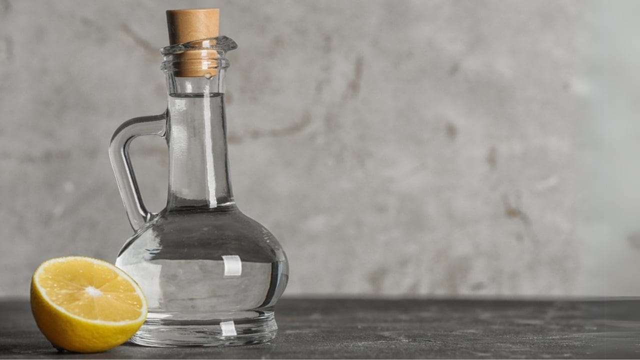 Ditch Chemicals with This Easy DIY Lemon Vinegar Cleaner - Glass jug with vinegar and lemon on table dp226641320 dnoh