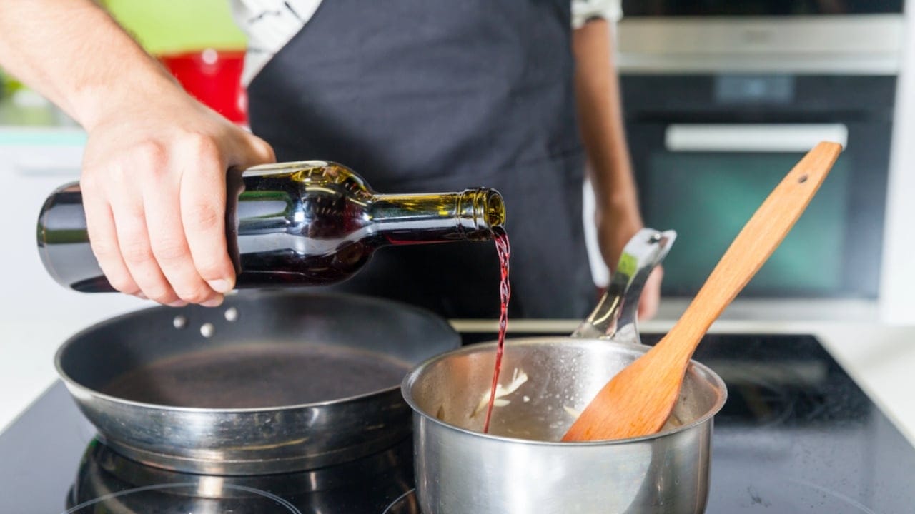 25 Genius Kitchen Tricks for Faster, Cheaper Meals 22 25 Genius Kitchen Tricks for Faster, Cheaper Meals - Mans hand pouring wine in pan dp126420848 dnoh