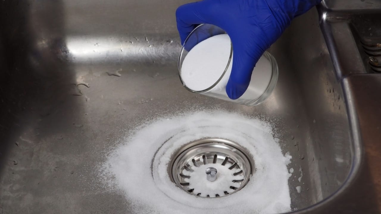 15 Natural Cleaning Recipes That Rival Chemical Products - pouring baking soda on drain kitchen sink ss2225119433 adyh