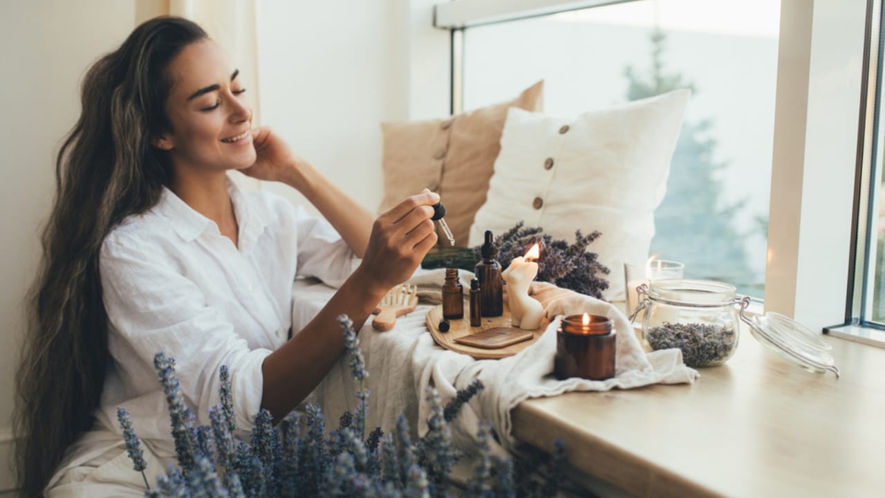 12 DIY Holiday Room Sprays to Bring Cheer to Every Room - woman applying natural organic essential oil ss2026508807 dnop