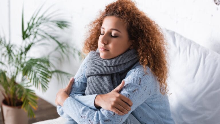 13 Ways to Stay Warm Without Cranking the Heat 10 13 Ways to Stay Warm Without Cranking the Heat - woman cold wearing sweater and scarf dp408056924 dnoh