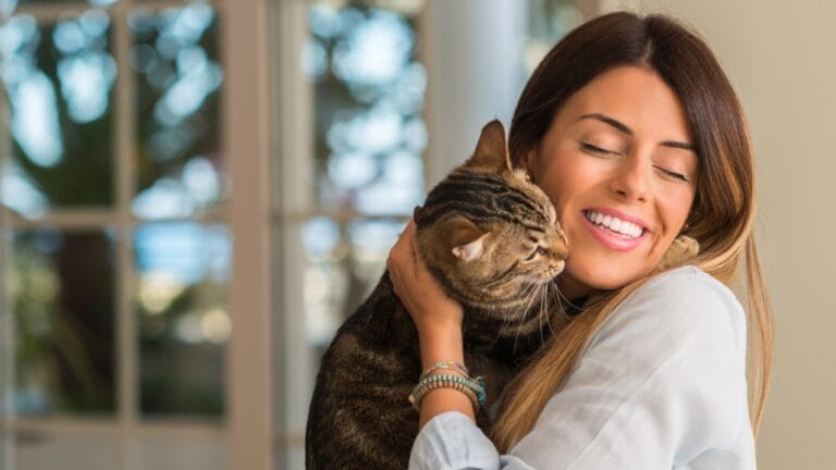 Cats Aren’t Just Cute—Here Are 20 Life-Changing Benefits - woman smiling and cuddling cat dp200442584 dnoh