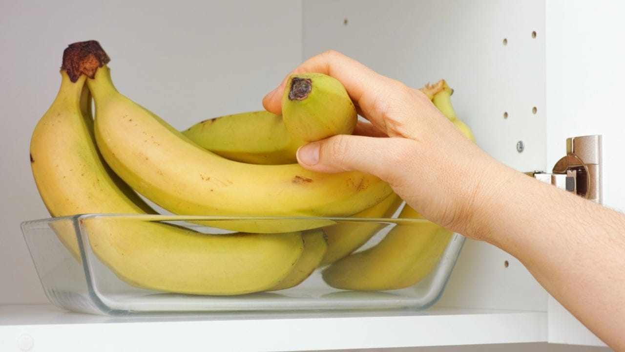 25 Genius Kitchen Tricks for Faster, Cheaper Meals 16 25 Genius Kitchen Tricks for Faster, Cheaper Meals - woman taking a bunch of bananas dp465681404 dnoh