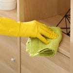 Say Goodbye to Greasy Cabinets with This Simple DIY Fix 5 Say Goodbye to Greasy Cabinets with This Simple DIY Fix - woman wearing gloves cleaning furniture cabinet dp243699698 dnoh